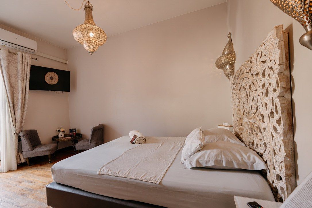 Chambre La Nomade de l’hôtel Ô Secret à Liège Chambre La Nomade de l'hôtel Ô Secret à Liège : lit king-size, tête de lit orientale sculptée et coin salon